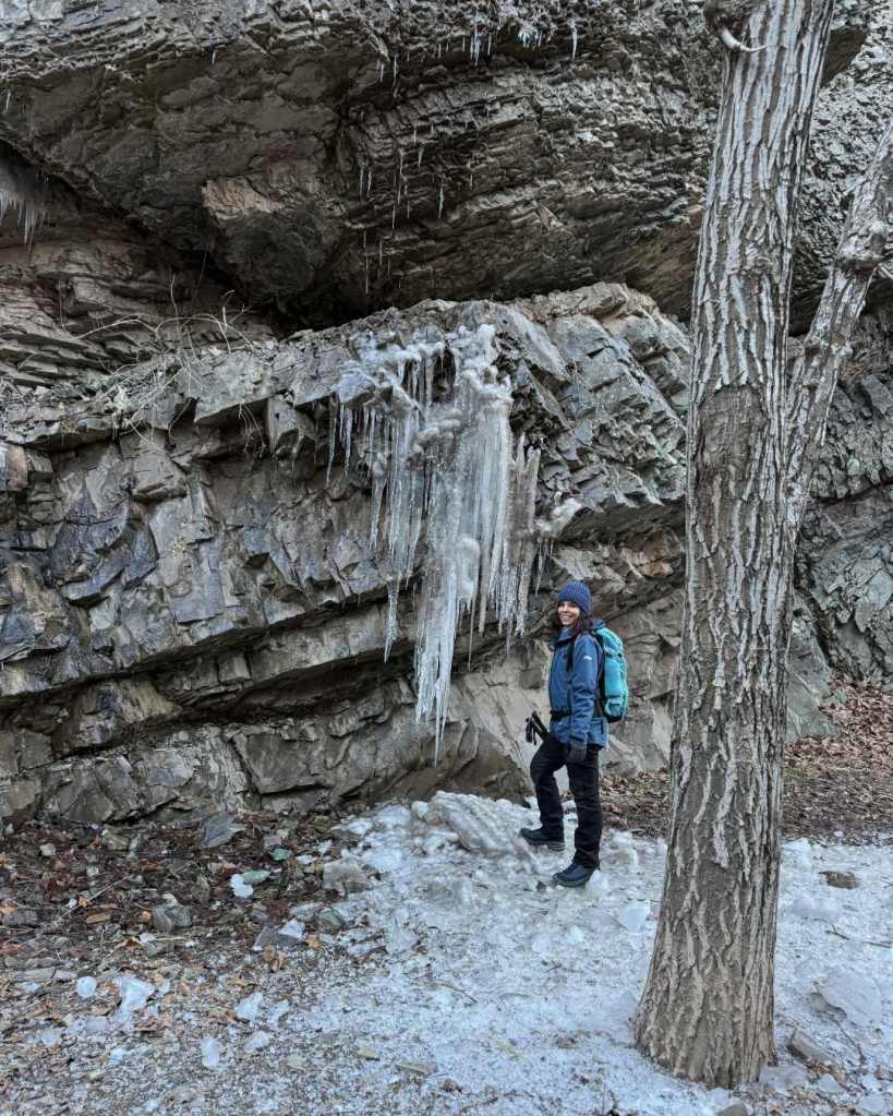Standing next to large rocks with frozen icicles in the mountains
