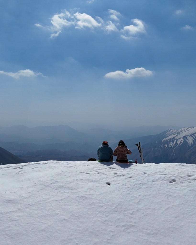 itting together on a snow-covered peak under a clear blue sky